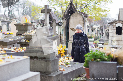 Image of Solitary woman visiting relatives grave.