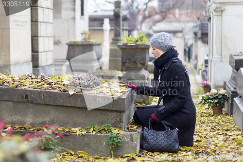 Image of Solitary woman visiting relatives grave.