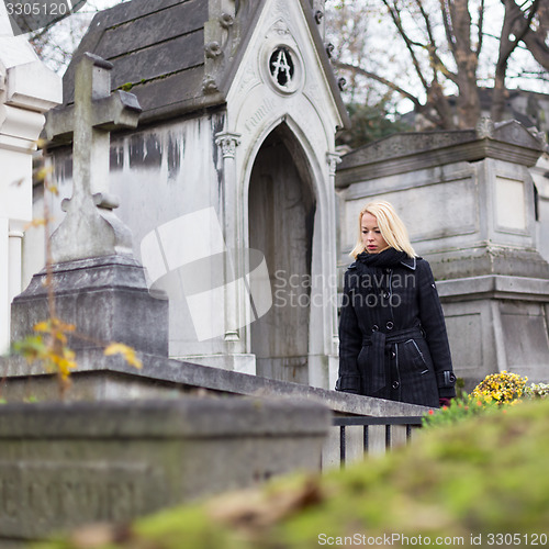 Image of Solitary woman visiting relatives grave.