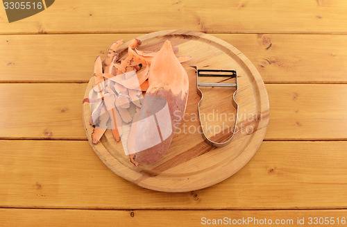 Image of Sweet potato with vegetable peeler on a chopping board