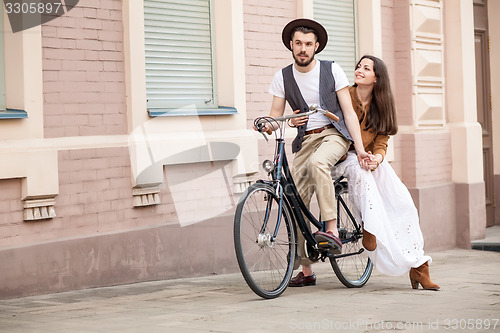 Image of Young couple sitting on a bicycle against the wall 