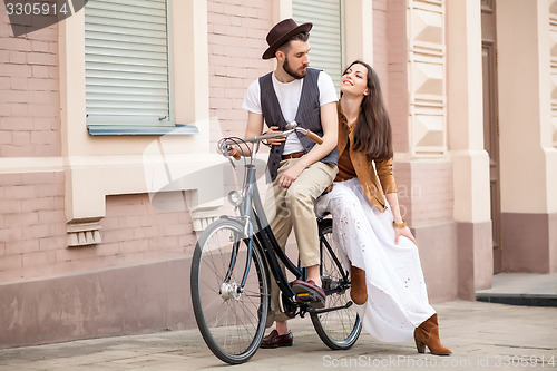 Image of Young couple sitting on a bicycle against the wall 