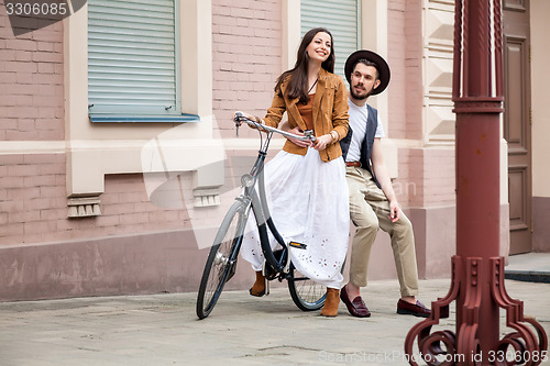 Image of Young couple sitting on a bicycle against the wall 