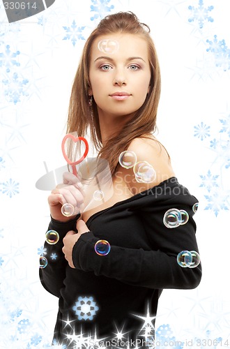 Image of lovely girl with heart-shaped blower and snowflakes