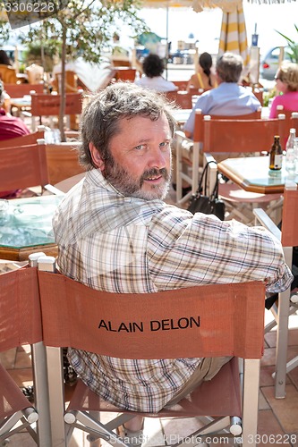 Image of CCANNES, FRANCE -  SEPTEMBER 17, 2008: Street cafe in Cannes. man sitting on  chair with the inscription Alain Delon