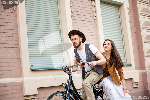 Image of Young couple sitting on a bicycle against the wall 