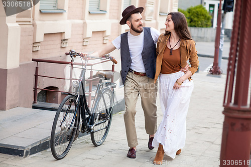 Image of Young couple walking with bicycle and hugging