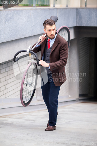 Image of Handsome businessman carrying his bicycle