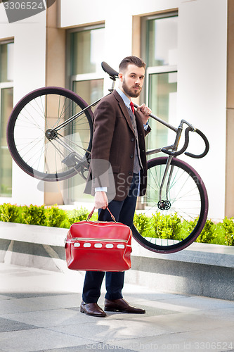 Image of Handsome businessman carrying his bicycle in office