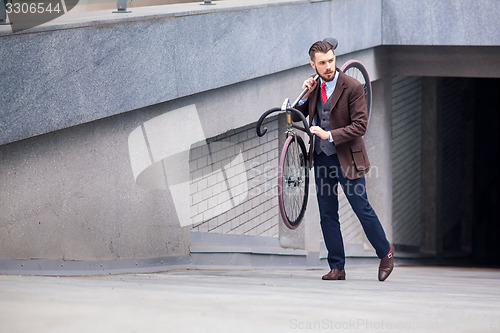 Image of Handsome businessman carrying his bicycle
