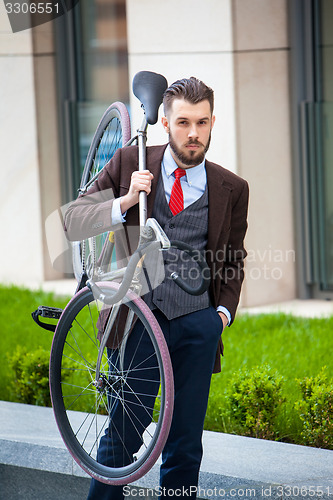 Image of Handsome businessman carrying his bicycle