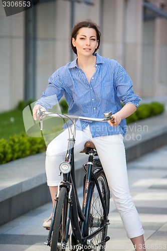 Image of Pretty girl sitting on a bicycle at street