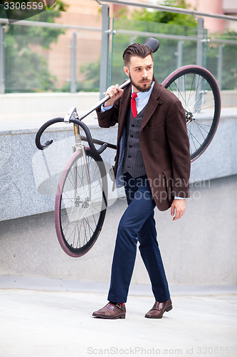 Image of Handsome businessman carrying his bicycle