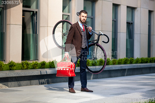 Image of Handsome businessman carrying his bicycle in office