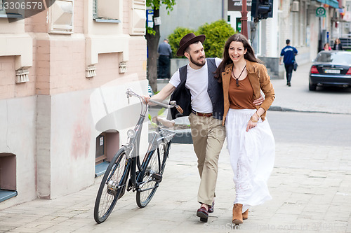 Image of Young couple walking with bicycle and hugging