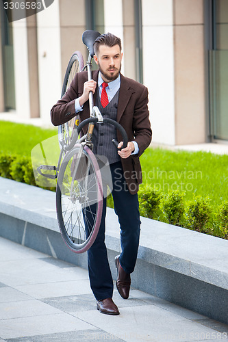 Image of Handsome businessman carrying his bicycle