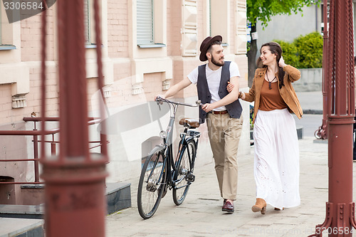 Image of Young couple walking with bicycle and hugging