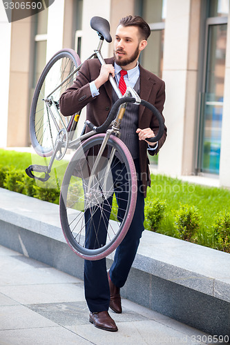 Image of Handsome businessman carrying his bicycle