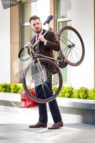 Image of Handsome businessman carrying his bicycle in his office