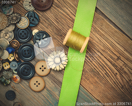 Image of vintage buttons, spool with thread and green tape
