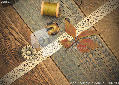 Image of still life with lace tape, vintage buttons, spools of thread and