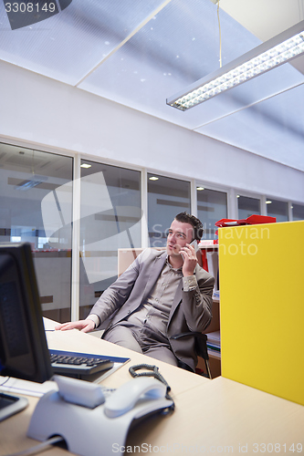Image of business man talking by phone in office