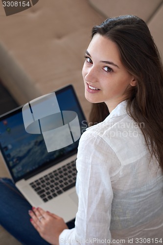 Image of relaxed young woman at home working on laptop computer