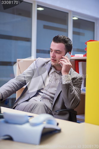 Image of business man talking by phone in office