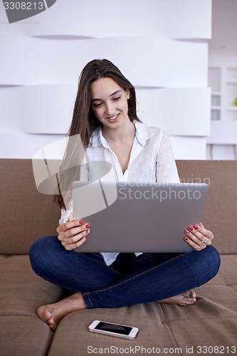 Image of relaxed young woman at home working on laptop computer