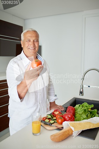 Image of man cooking at home preparing salad in kitchen