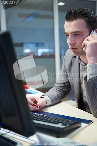 Image of business man talking by phone in office