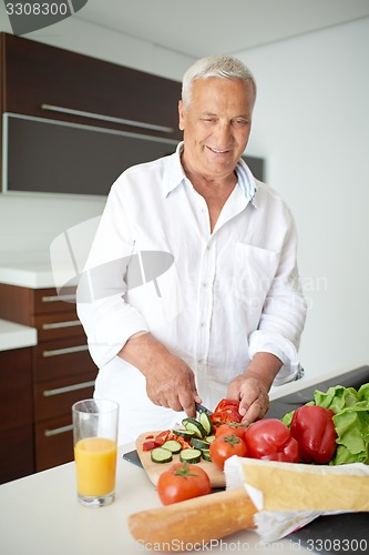 Image of man cooking at home preparing salad in kitchen