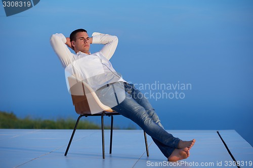 Image of relaxed young man at home on balcony