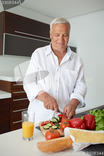 Image of man cooking at home preparing salad in kitchen