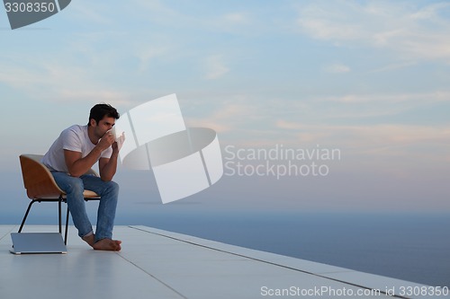 Image of relaxed young man at home on balcony