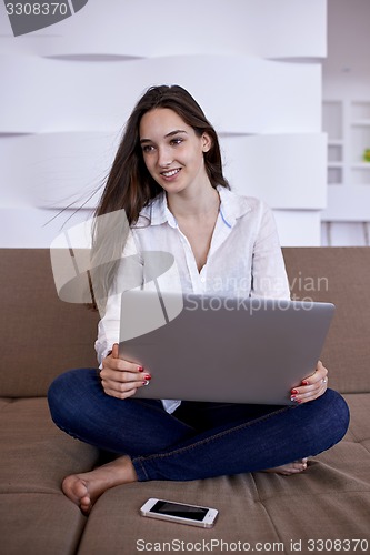 Image of relaxed young woman at home working on laptop computer