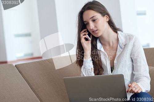 Image of relaxed young woman at home working on laptop computer