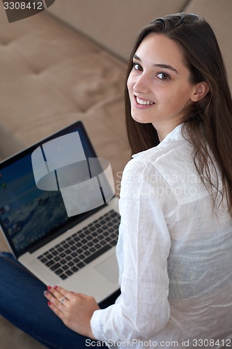 Image of relaxed young woman at home working on laptop computer