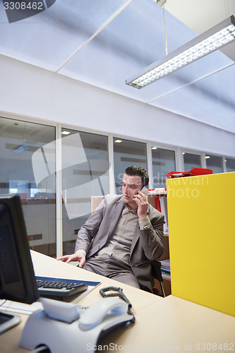 Image of business man talking by phone in office