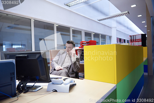 Image of business man talking by phone in office