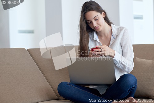 Image of relaxed young woman at home working on laptop computer