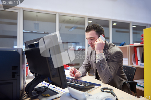 Image of business man talking by phone in office