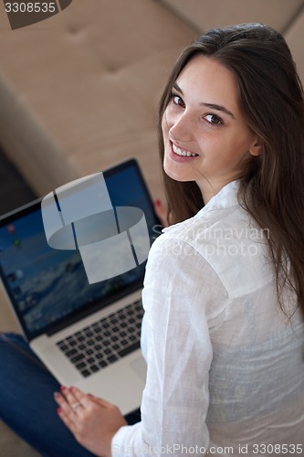 Image of relaxed young woman at home working on laptop computer