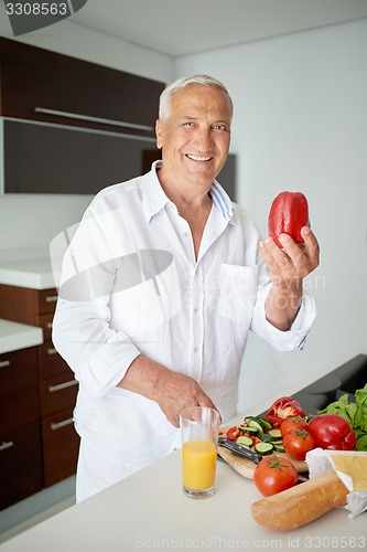 Image of man cooking at home preparing salad in kitchen