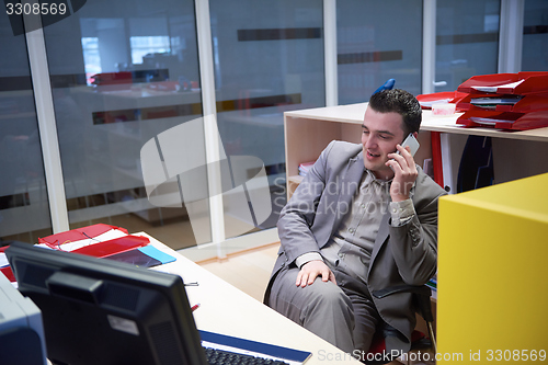 Image of business man talking by phone in office