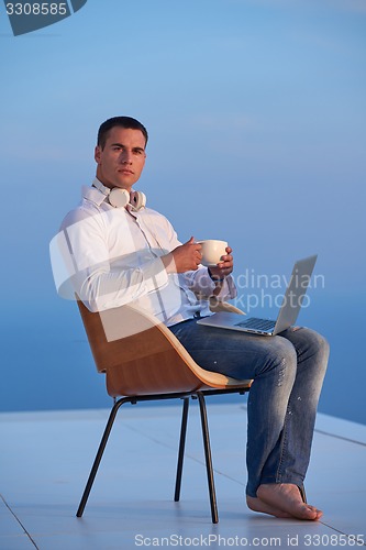 Image of relaxed young man at home on balcony