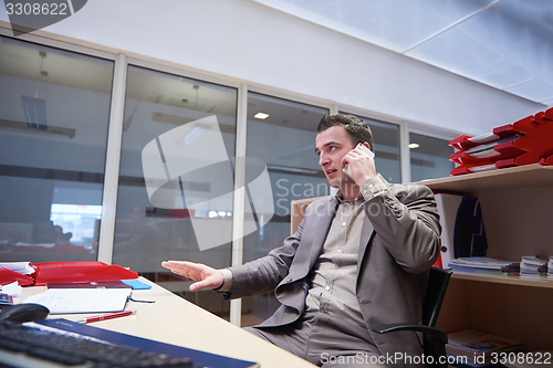 Image of business man talking by phone in office