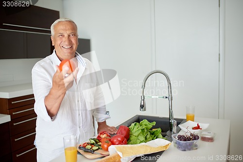 Image of man cooking at home preparing salad in kitchen