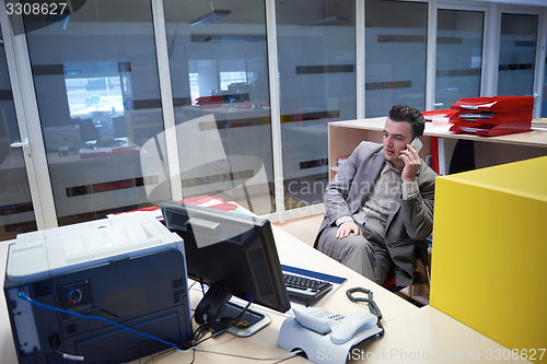 Image of business man talking by phone in office
