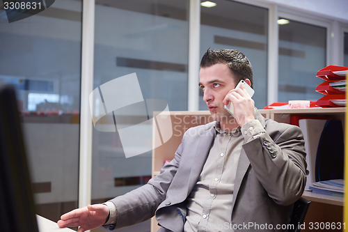 Image of business man talking by phone in office